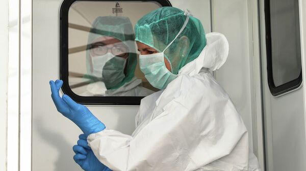 Врач надевает перчатки в дезинфекционном туннеле больницы с коронавирусом  - Sputnik Қазақстан