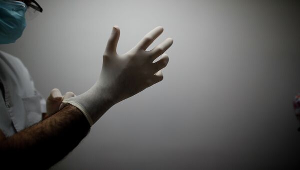 Врач в больнице с коронавирусом надевает перчатки - Sputnik Қазақстан