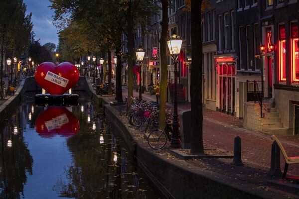 Красное сердце с напоминанием соблюдать социальную дистанцию в почти пустом квартале красных фонарей в Амстердаме, Нидерланды - Sputnik Қазақстан