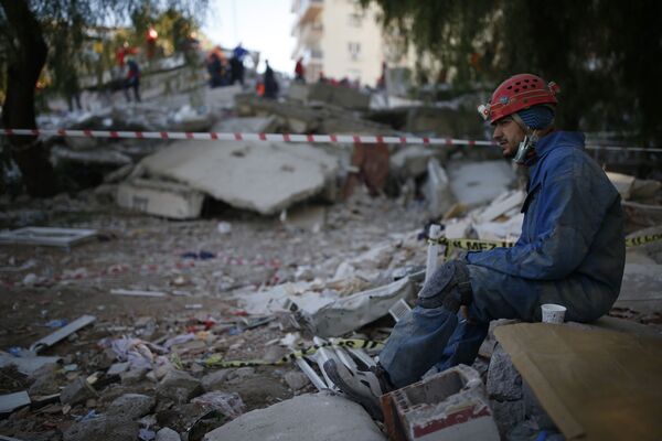 Спасатель во время отдыха на месте разрушенного здания после землетрясения в Измире  - Sputnik Казахстан