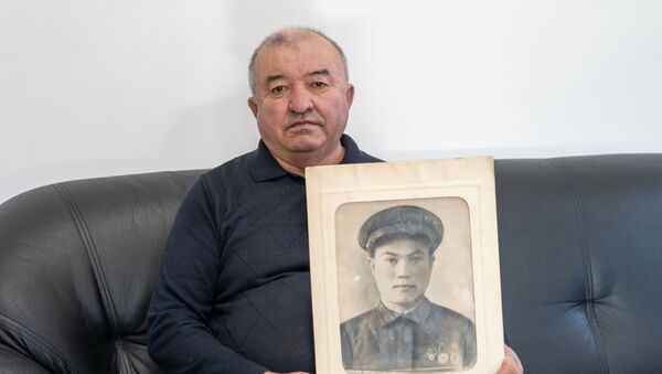 Внук найденного солдата Зимней войны Жумабек Мусин держит в руках портрет деда - Sputnik Қазақстан