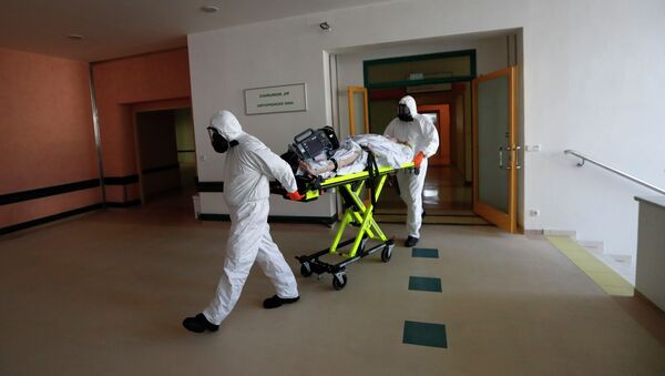 Медики в защитных костюмах везут на носилках пациента в больнице с коронавирусом  - Sputnik Казахстан