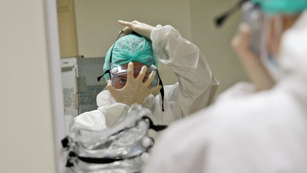 Врач надевает защитный костюм в больнице с коронавирусом  - Sputnik Казахстан