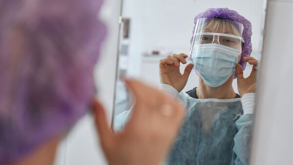 Медсестра поправляет лицевой щиток перед сменой в больнице с коронавирусом  - Sputnik Казахстан