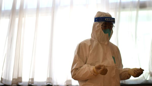 Врач в защитном костюме стоит у окна в больнице с коронавирусом  - Sputnik Казахстан