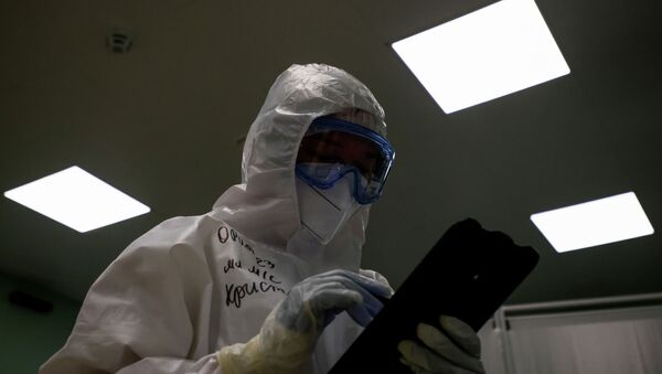 Врач в защитном костюме работает на планшете с данными пациентов в больнице с коронавирусом  - Sputnik Казахстан