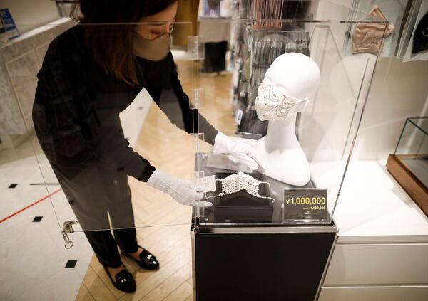 Сотрудник магазина устанавливает маску с драгоценными камнями  в Токио  - Sputnik Казахстан