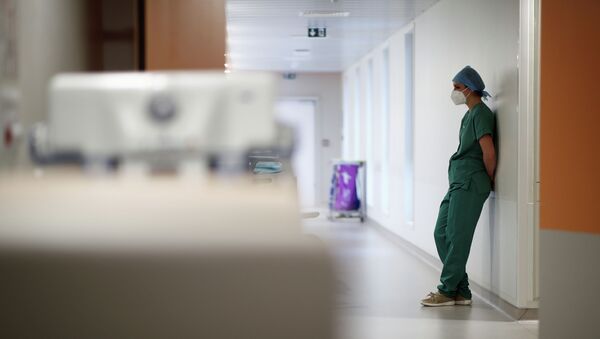 Врач в защитной маске стоит, опираясь на стену, в больнице с коронавирусом  - Sputnik Казахстан