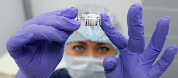 Медсестра держит в руках пузырек с вакциной Спутник V Медсестра держит в руках пузырек с вакциной Спутник V - Sputnik Казахстан