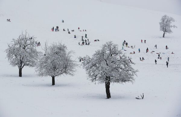Люди катаются на санках во время первого снегопада в Альбиспассе, Швейцария - Sputnik Казахстан