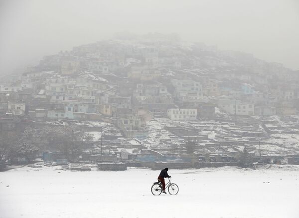 Велосипедист во время снегопада на фоне заснеженного Кабула, Афганистан - Sputnik Казахстан