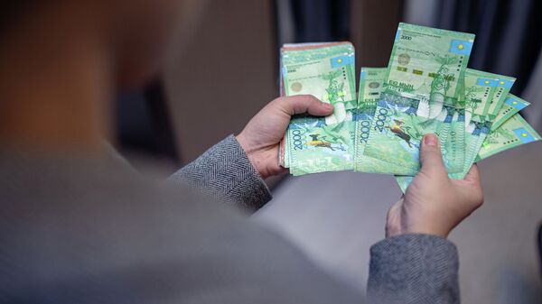 Человек держит в руках бумажные деньги  - Sputnik Казахстан