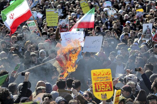 Иранские демонстранты сжигают флаг США во время митинга, посвященного 41-й годовщине Исламской революции в Тегеране - Sputnik Казахстан