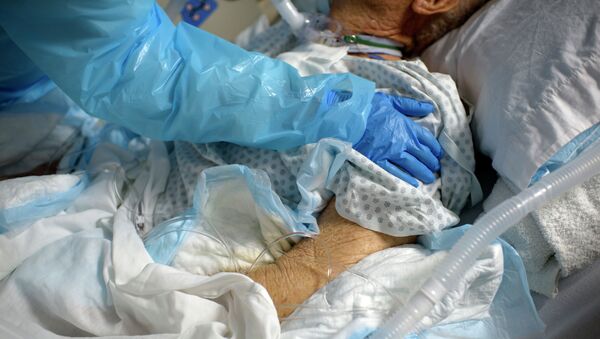 Медик осматривает пожилого пациента в палате интенсивной терапии в больнице с коронавирусом  - Sputnik Қазақстан