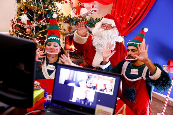 Мужчина в костюме Санта-Клауса и его помощники в костюмах эльфов во время общения через Zoom с детьми в Риме, Италия - Sputnik Казахстан