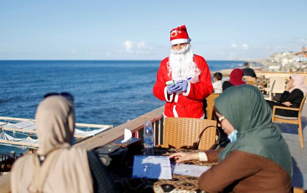 Палестинец в костюме Санта-Клауса в пляжном кафе в Газе - Sputnik Казахстан