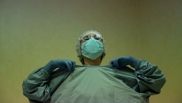 Врач надевает защитный костюм перед началом дежурства в больнице с коронавирусом  - Sputnik Казахстан