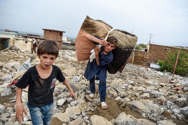 Молодые люди спасают остатки вещей из развалин домов после внезапного наводнения в Чарикаре, провинция Парван, Афганистан - Sputnik Казахстан