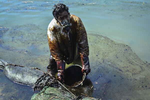Мужчина очищает воду от разлившейся у берегов Маврикия нефти - Sputnik Казахстан