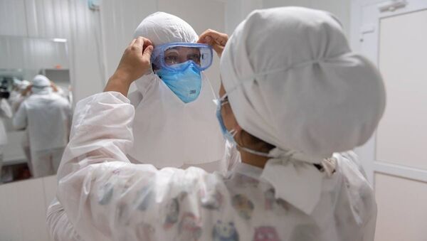 Врач снимает защитный костюм после окончания дежурства в больнице с коронавирусом - Sputnik Казахстан