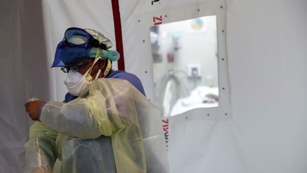 Врач снимает защитный костюм после завершения дежурства в больнице с коронавирусом  - Sputnik Казахстан