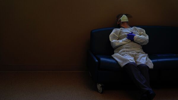 Медик в защитной маске отдыхает между приемом пациентов в больнице с коронавирусом  - Sputnik Казахстан