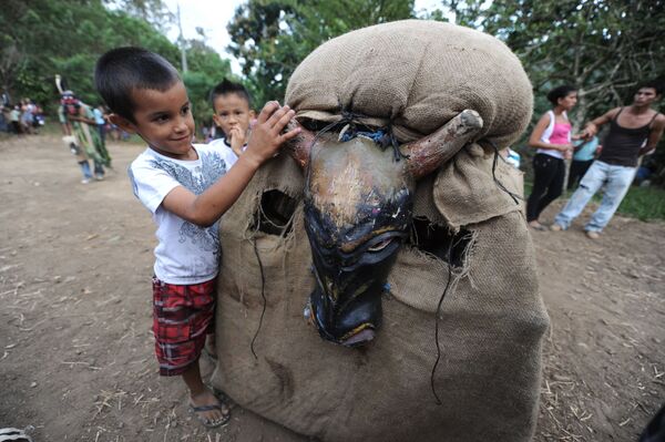 Мальчик играет с участником фестиваля Feast of the Devils в костюме быка в Коста-Рике  - Sputnik Казахстан