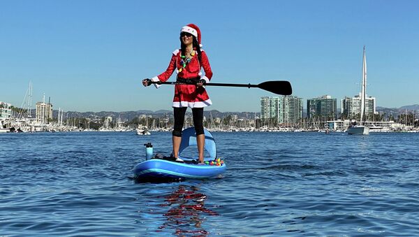 Девушка в костюме Санта-Клауса на SUP-серфе в Лос-Анджелесе, Калифорния - Sputnik Казахстан