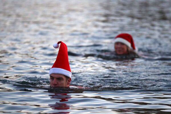 Люди в рождественских колпаках плаваю в озере Серпентин в Гайд-парке в Лондоне - Sputnik Казахстан