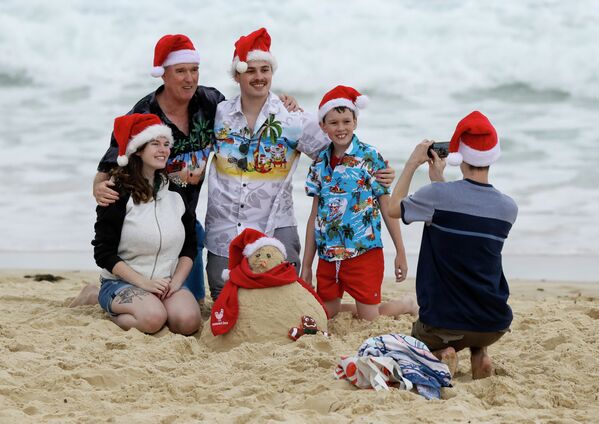 Семья в рождественских колпаках фотографируется на пляже в Сиднее, Австралия  - Sputnik Казахстан