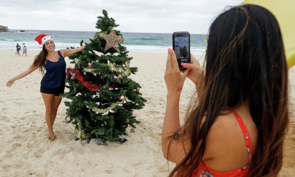 Девушки фотографируются у рождественской ели на пляже в Сиднее, Австралия  - Sputnik Казахстан