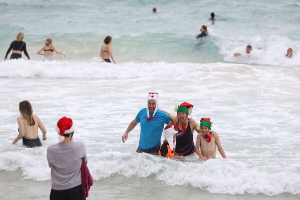 Люди в рождественской одежде позируют для фотографий в Рождество на пляже Бонди в Сиднее, Австралия - Sputnik Казахстан