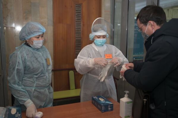 На входе в избирательный участок голосующим предлагают надеть перчатки - Sputnik Казахстан