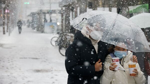 Пара в масках спасается от снегопада под прозрачным зонтом  - Sputnik Казахстан
