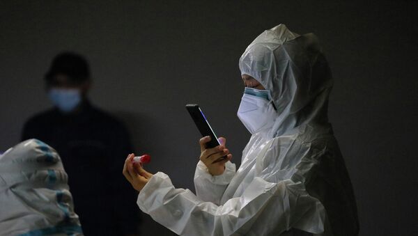 Медик в защитном костюме фотографирует маркированную пробирку с ПЦР-тестом для анализа на коронавирус - Sputnik Казахстан