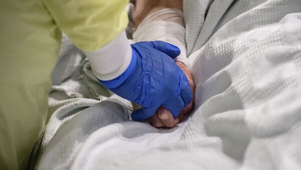 Врач держит за руку пожилого пациента палаты интенсивной терапии в больнице с коронавирусом - Sputnik Казахстан