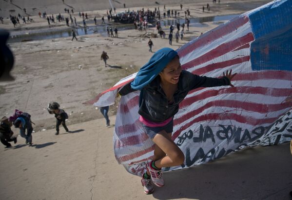 Женщина-мигрантка с флагом на границе США и Мексики - Sputnik Казахстан