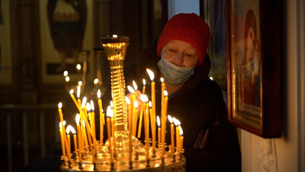 Женщина ставит свечи в церкви в Крещение  - Sputnik Казахстан