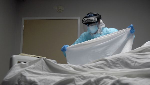 Медик в защитном костюме накрывает тело погибшего от коронавируса пациента  - Sputnik Қазақстан