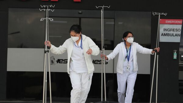 Медсестры в защитных масках перевозят штативы для капельниц в больнице с коронавирусом - Sputnik Казахстан