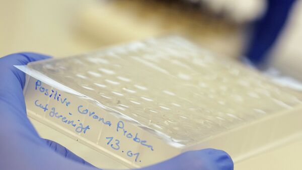 Сотрудник лаборатории держит в руках пробирки с положительными пробами на коронавирус - Sputnik Қазақстан