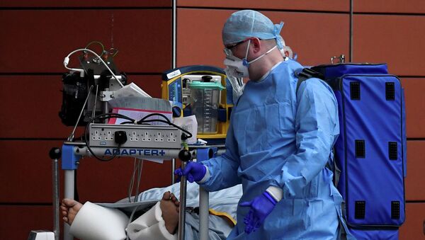 Медик в защитном костюме транспортирует пациента с коронавирусом в больницу  - Sputnik Казахстан