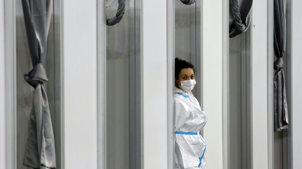 Медик в защитном костюме стоит у окна больницы с коронавирусом  - Sputnik Қазақстан