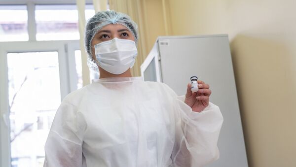 Медик в защитном костюме держит пузырек с вакциной  - Sputnik Казахстан