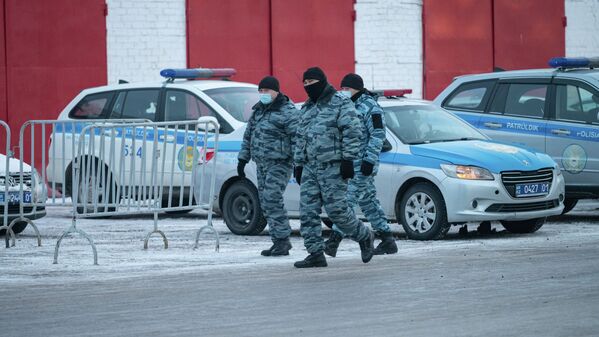 Полицейские в масках идут мимо припаркованных автомашин - Sputnik Қазақстан