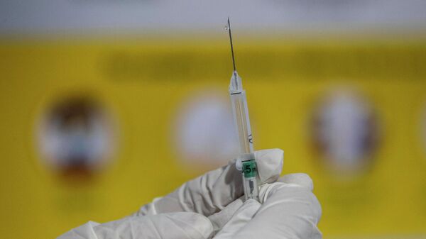 Медик держит в руках шприц с вакциной от коронавируса  - Sputnik Казахстан