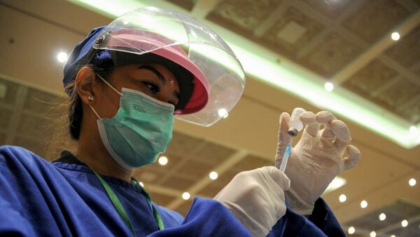 Медработник в защитном костюме набирает вакцину от коронавируса в шприц  - Sputnik Қазақстан