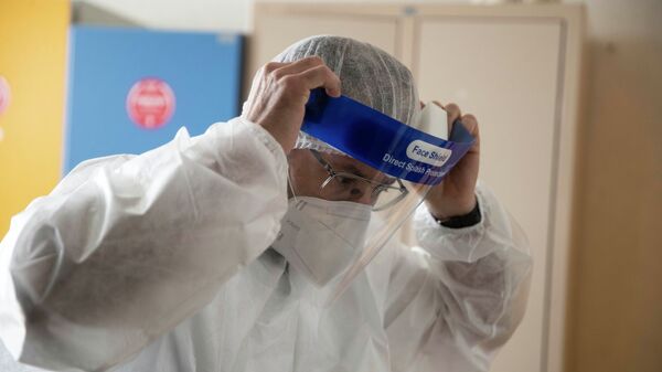 Врач поправляет защитный лицевой щиток перед началом смены в больнице с коронавирусом  - Sputnik Казахстан