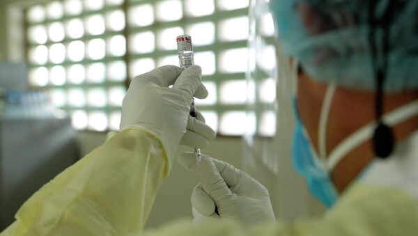 Медик в защитном костюме набирает в шприц вакцину от коронавируса - Sputnik Казахстан