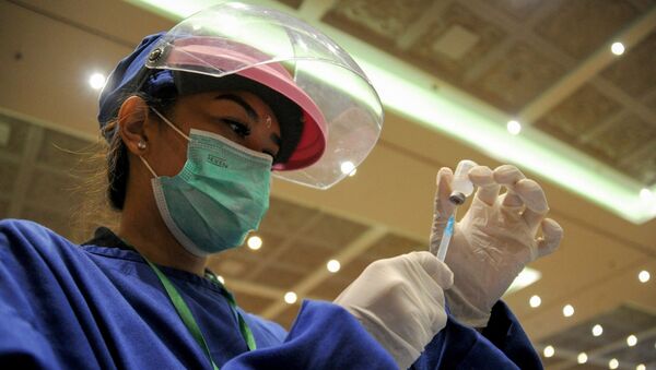 Медик в защитном костюме набирает в шприц вакцину от коронавируса  - Sputnik Казахстан